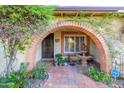 Inviting entryway with brick archway, fountain, and tiled flooring, showcasing unique charm at 6255 E Crocus Dr, Scottsdale, AZ 85254