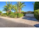 Inviting home exterior with palm trees, lush landscaping, and a well-maintained two-car garage at 6255 E Crocus Dr, Scottsdale, AZ 85254