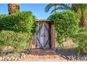 Rustic wooden gate surrounded by lush greenery, adding character and privacy to the property at 6255 E Crocus Dr, Scottsdale, AZ 85254