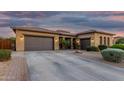 Stunning exterior elevation showcases a three-car garage and desert landscaping at twilight at 20211 E Via Del Oro --, Queen Creek, AZ 85142
