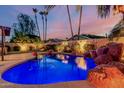 Backyard pool with rock waterfall feature and palm trees, perfect for entertaining at 2108 E Patrick Ln, Phoenix, AZ 85024