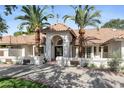 Elegant home with a well-manicured lawn, mature palm trees, and a stunning arched entrance at 10300 N 48Th Pl, Paradise Valley, AZ 85253