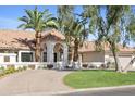 Beautiful single-story home showcasing lush landscaping, a circular driveway, and an elegant arched entryway at 10300 N 48Th Pl, Paradise Valley, AZ 85253