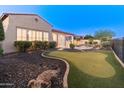 Spacious backyard with a lush lawn, putting green, mature trees, and a covered patio overlooking the beautiful pool at 12809 W Oyer Ln, Peoria, AZ 85383