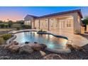 Backyard oasis featuring a free form pool with rock accents, a covered patio, and lush landscaping at 12809 W Oyer Ln, Peoria, AZ 85383