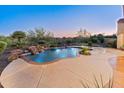 Backyard view of sparkling pool with waterfall feature, surrounded by lush landscaping and a spacious patio area at 12809 W Oyer Ln, Peoria, AZ 85383