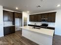 Modern kitchen featuring dark wood cabinets, white countertops, stainless steel appliances, and a large island at 17535 W Fulton St, Goodyear, AZ 85338