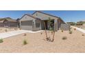 New single-story home with a two-car garage, desert landscaping, and concrete driveway on a sunny day at 18340 W Patrick Ln, Surprise, AZ 85387