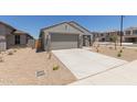 Single-story house with two-car garage, desert landscaping, and a view of the neighborhood on a sunny day at 18340 W Patrick Ln, Surprise, AZ 85387