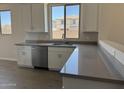 Close-up of the kitchen featuring stainless steel dishwasher, sink, and modern gray countertops at 18340 W Patrick Ln, Surprise, AZ 85387
