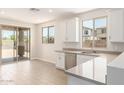 Bright kitchen featuring white cabinets, stainless steel appliances, gray countertops, and wood-look tile flooring at 18340 W Patrick Ln, Surprise, AZ 85387