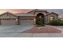 Single-story home with a terracotta roof, arched entry, and three-car garage, and low-maintenance desert landscaping at 2058 E Marlene Dr, Gilbert, AZ 85296
