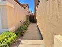 Side view of a walkway leading to a private gate, enhanced by verdant landscaping and desert flora at 3440 E Southern Ave # 1088, Mesa, AZ 85204