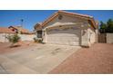 Single-story home with a two-car garage and low-maintenance desert landscaping in the front yard at 7603 W Oraibi Dr, Glendale, AZ 85308