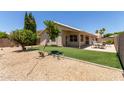 View of the backyard featuring a covered patio, artificial grass, and desert landscaping at 9559 W Runion Dr, Peoria, AZ 85382