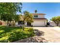 Charming two-story home boasts a well-maintained lawn, mature trees, and a two-car garage at 1353 W Kiowa Ave, Mesa, AZ 85202