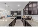 Contemporary kitchen featuring dark cabinetry, stainless steel appliances, and granite countertops at 15276 W Latham St, Goodyear, AZ 85338