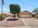 Charming one-story home boasting a well-kept lawn, mature shade tree, and an attached two-car garage at 15505 N 135Th Dr, Surprise, AZ 85374