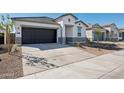 Charming single-story home with a modern facade, dark garage door, and a concrete driveway at 25471 W Fraktur Rd, Buckeye, AZ 85326