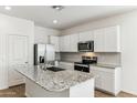 Modern kitchen with stainless steel appliances, granite countertops, white cabinetry, and a large island at 25477 W Fraktur Rd, Buckeye, AZ 85326