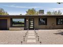 The front of this home features a gravel yard, walkway lighting, and a modern glass front door at 7620 N 12Th Pl, Phoenix, AZ 85020
