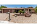 Single-story home featuring xeriscaping, brick accents, and desert vegetation in the front yard at 8620 E Sells Dr, Scottsdale, AZ 85251