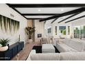 Bright living room featuring a stone fireplace, wood floors, and black wood beam ceilings at 908 W Pershing Ave, Phoenix, AZ 85029