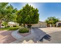 Traditional home with a three car garage and well-maintained landscaping including a large tree and desert foliage at 91 W Baylor Ln, Gilbert, AZ 85233