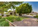 Beautiful home with arched entryways, manicured front lawn, desert landscaping, and mature shade trees at 91 W Baylor Ln, Gilbert, AZ 85233