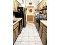 Galley kitchen featuring tile flooring, wood cabinets, and black appliances at 1231 E Avila Ave, Casa Grande, AZ 85122