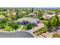 Stunning home with lush green lawn, mature trees, and a circular driveway, set against a backdrop of distant mountains at 1940 N Stevens Cir, Mesa, AZ 85205
