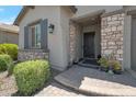 Home featuring a stone pillar entrance with a black front door and manicured landscaping at 41215 W Almira Dr, Maricopa, AZ 85138