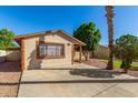 View of a single-story tan home with brown trim and a well-manicured yard at 5649 W Holly St, Phoenix, AZ 85035