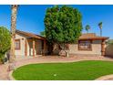 Single-story home featuring mature landscaping, a manicured lawn, and a cozy front porch at 5649 W Holly St, Phoenix, AZ 85035