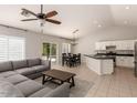 Open-concept living space with a comfortable gray couch, bright kitchen, and sliding door access to the backyard at 9212 W Salter Dr, Peoria, AZ 85382