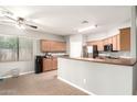Eat-in kitchen featuring tile flooring, wood cabinets, and peninsula with countertop dining at 17562 W Gelding Dr, Surprise, AZ 85388