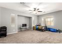 Open-concept living room with neutral tones, carpet flooring, and a ceiling fan at 17562 W Gelding Dr, Surprise, AZ 85388