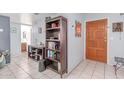 Inviting entryway with tile floors, decorative mirror, wooden door, and storage bookshelf at 2020 W Union Hills Dr # 156, Phoenix, AZ 85027
