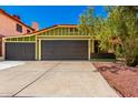 Inviting curb appeal with a green home exterior, flowering tree, three car garage and well-manicured landscaping at 2109 E Gelding Dr, Phoenix, AZ 85022