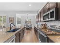 Open-concept kitchen featuring dark wood cabinets, granite countertops, stainless appliances, and hardwood floors at 2459 E Lindrick Dr, Gilbert, AZ 85298