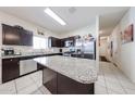 Spacious kitchen featuring dark cabinetry, granite countertops, stainless steel appliances and tile flooring at 30186 W Pinchot Ave, Buckeye, AZ 85396