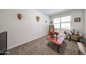 A cozy living room featuring carpeted floors, a window with blinds, and decorative wall masks and a table with flowers at 30186 W Pinchot Ave, Buckeye, AZ 85396