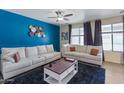 Bright living room featuring a dark blue accent wall, plush furniture, and large windows for lots of natural light at 4933 W Melody Ln, Laveen, AZ 85339