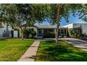 Attractive single-story home features a well-manicured lawn, mature trees, and brick-paved walkway at 1522 W Willetta St, Phoenix, AZ 85007