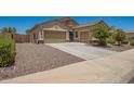 View of the three-car garage with desert landscaping for low maintenance and curb appeal at 18474 W College Dr, Goodyear, AZ 85395