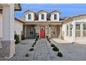 Striking single-story home with a welcoming red door, beautiful landscaping, and a brick pathway at 19910 E Vallejo St, Queen Creek, AZ 85142