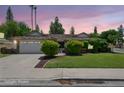 Charming single-story home featuring a well-manicured lawn, mature trees, and a two-car garage with a light brown roof at 2053 W Natal Cir, Mesa, AZ 85202