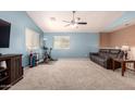 Spacious bonus room featuring a ceiling fan, exercise bike, large windows and a sofa at 40316 W Hopper Dr, Maricopa, AZ 85138