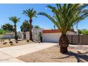 Charming white home with desert landscaping, wrought iron gate and numerous palm trees at 5211 E Winchcomb Dr, Scottsdale, AZ 85254