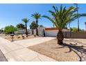 Charming white home with desert landscaping, a two-car garage and numerous palm trees at 5211 E Winchcomb Dr, Scottsdale, AZ 85254